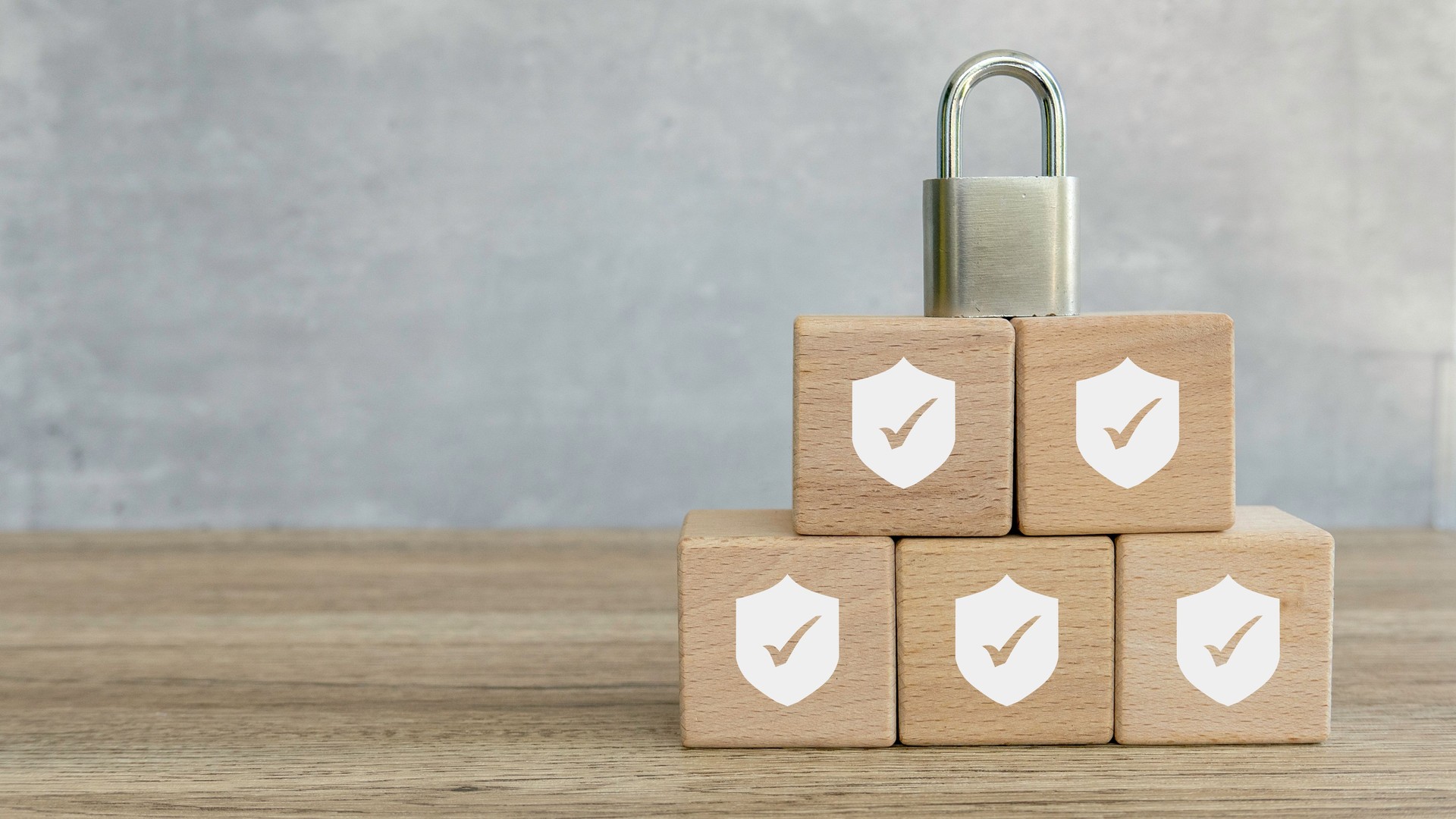 Security Concept: Wooden Blocks with Shield and Checkmark Icons Stacked with Padlock on Top